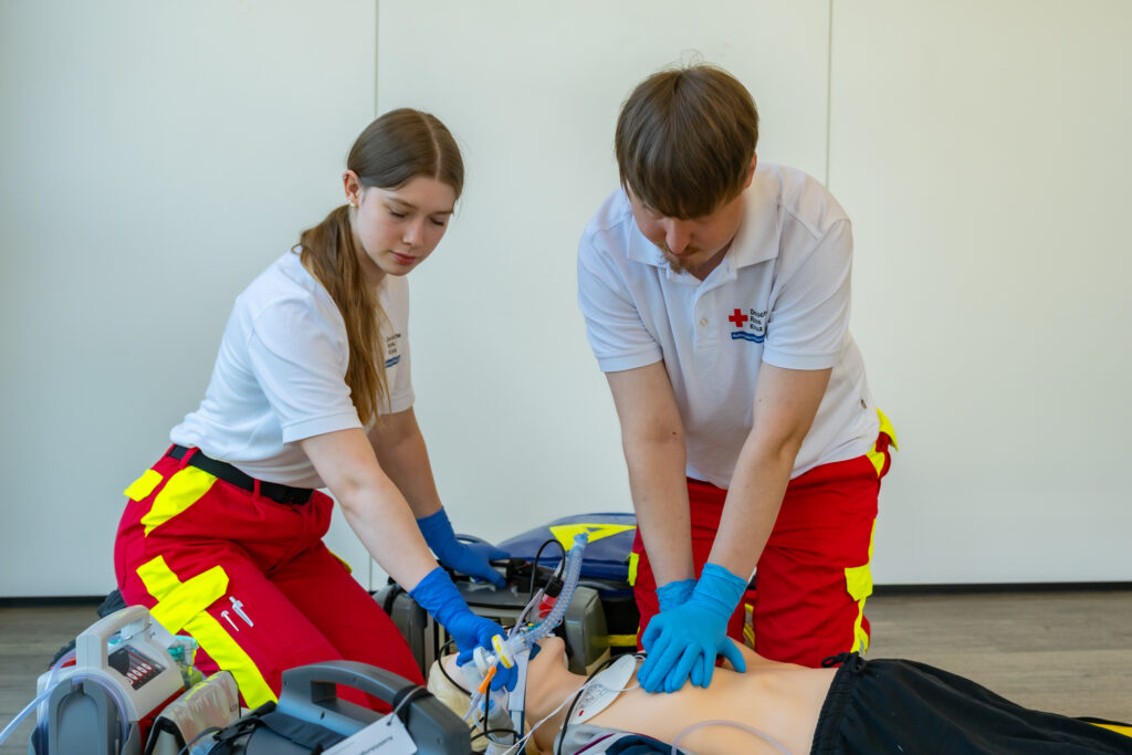 Zwei Teilnehmer der Rettungsdienstschule trainieren Beatmung und Herzdruckmassage an einer Reanimationspuppe.