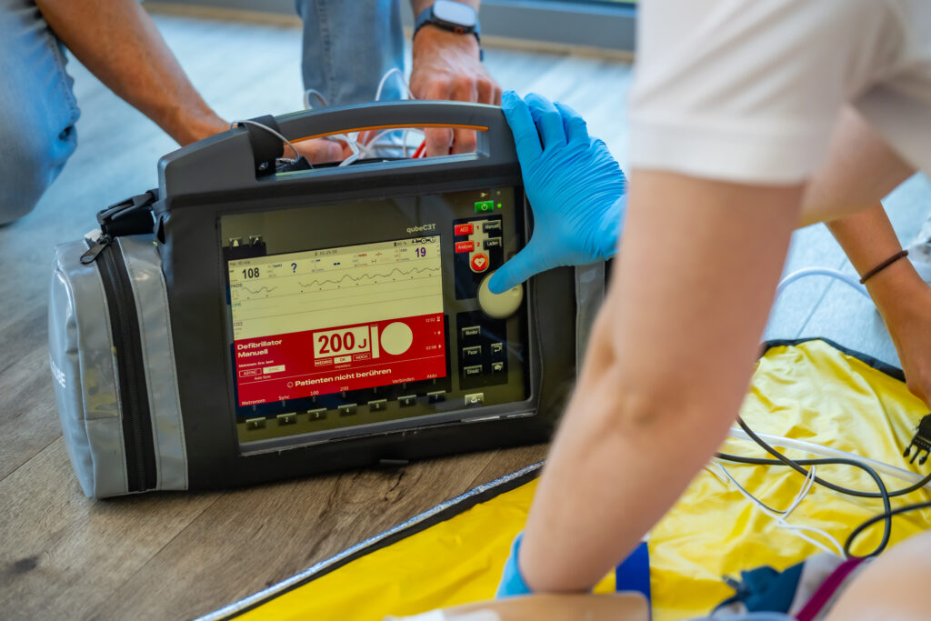 Teilnehmer bedienen während einer Reanimationsübung einen Defibrillator, der auf 200 Joule eingestellt ist.